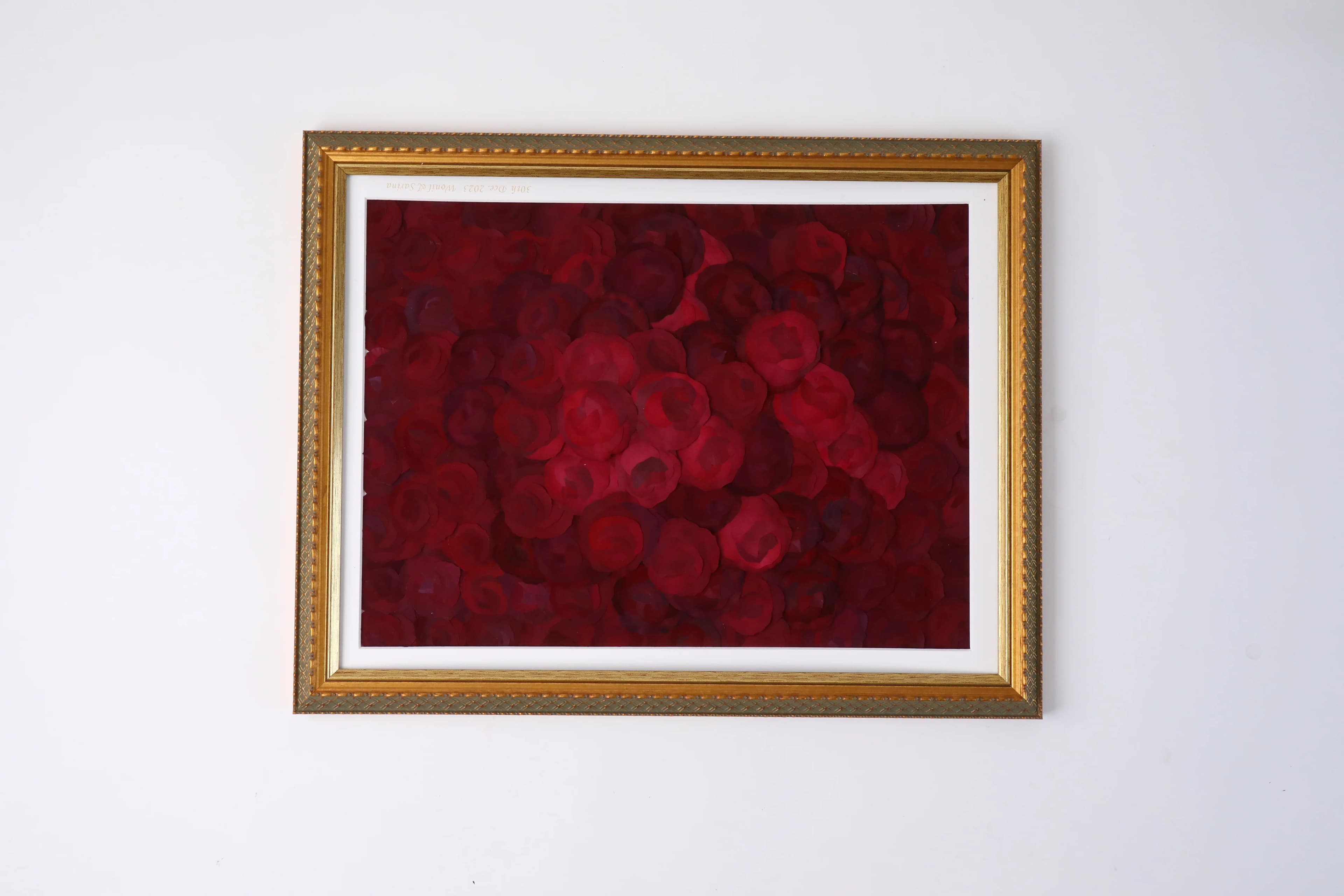白い壁に掛けた金縁の額に赤いバラを収めた押し花作品